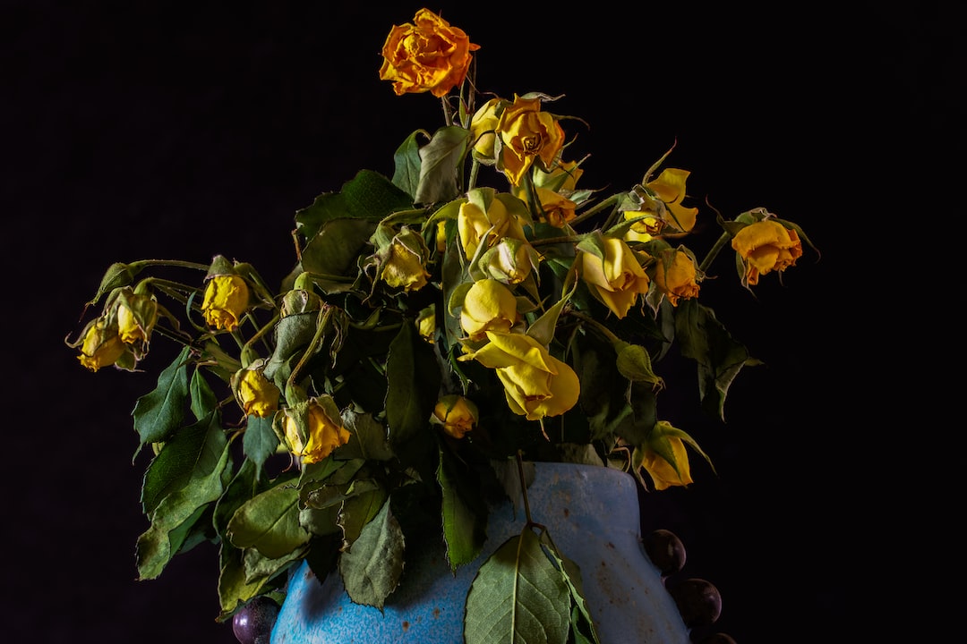 a blue vase filled with yellow flowers on top of a table