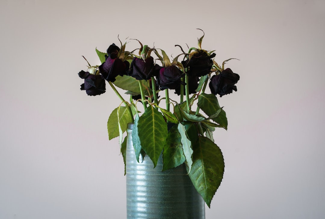 a green vase filled with purple flowers on top of a table